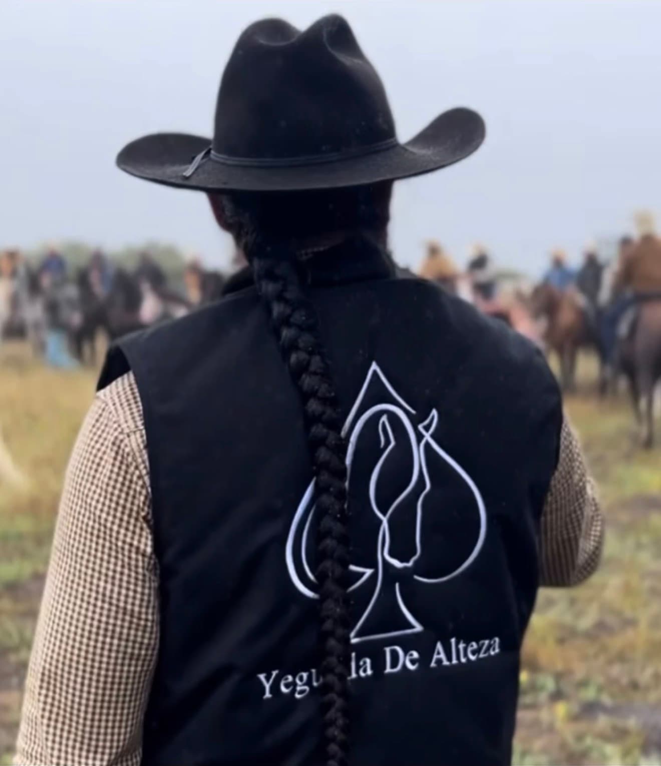 A rider in a black hat looking out over a foggy field, with other riders on horseback behind him