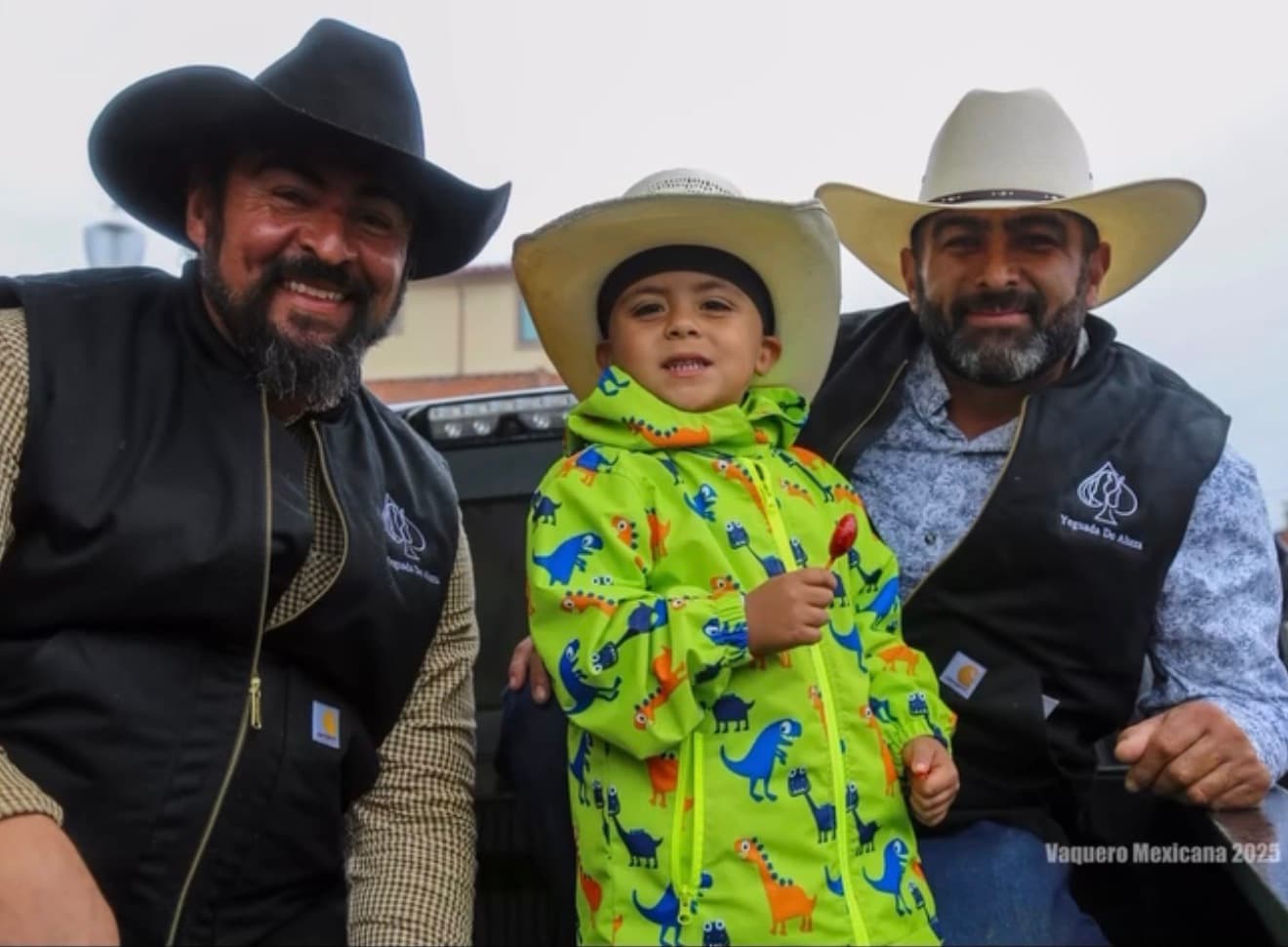 Two riders and a child in a rain jacket posing together at the event
