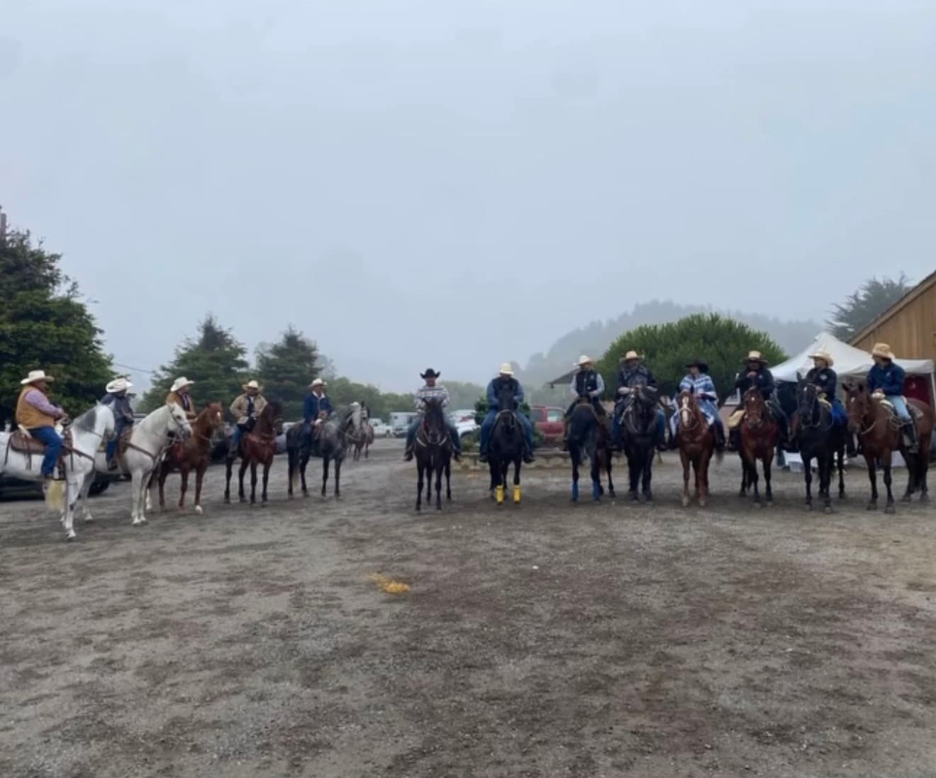 Riders lined up on horseback in a gravel staging area